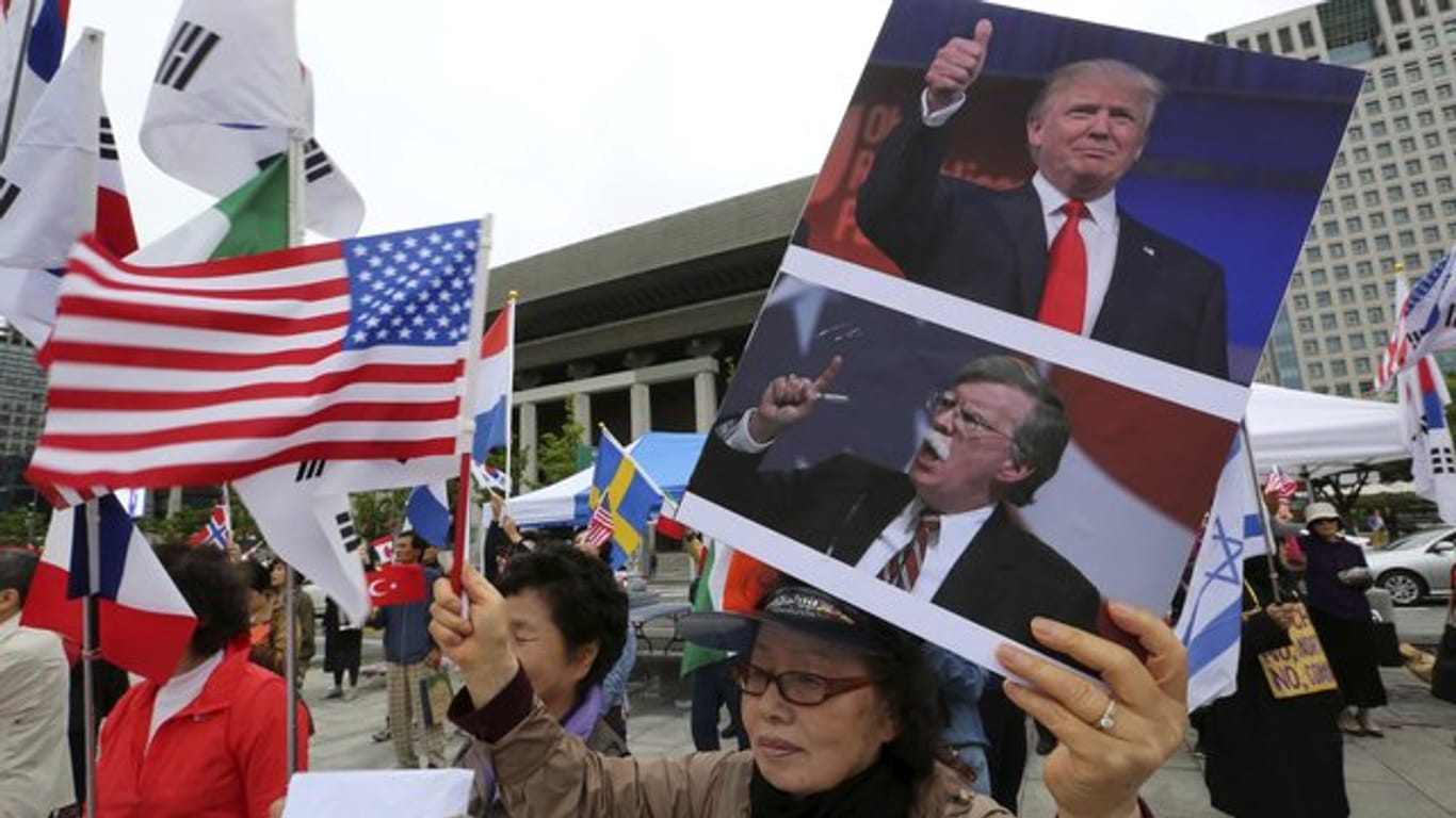 Eine Demonstrantin wirbt mit Bildern von Donald Trump und US-Sicherheitsberater Bolton für die strenge Nordkorea-Politik der USA.