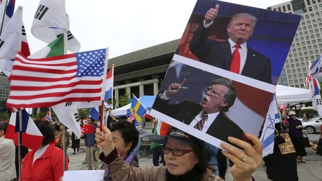 Eine Demonstrantin wirbt mit Bildern von Donald Trump und US-Sicherheitsberater Bolton für die strenge Nordkorea-Politik der USA. Eine Demonstrantin wirbt mit Bildern von Donald Trump und US-Sicherheitsberater Bolton für die strenge Nordkorea-Politik der USA.