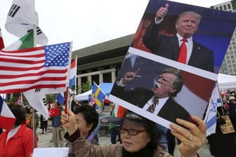 Eine Demonstrantin wirbt mit Bildern von Donald Trump und US-Sicherheitsberater Bolton für die strenge Nordkorea-Politik der USA.