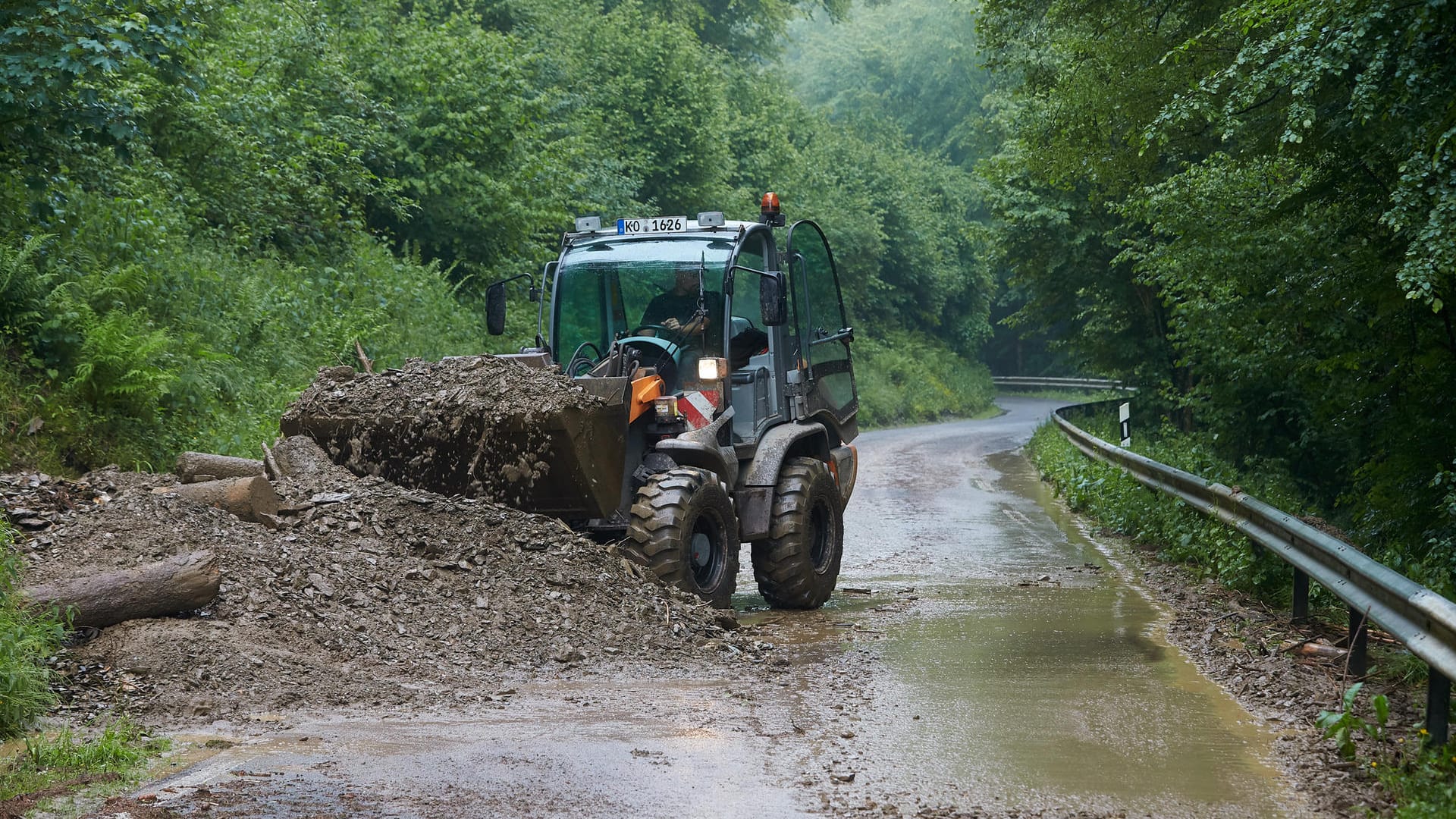 Bergungskräfte räumen mit Hilfe eines Radladers Erde von der Landesstrasse 113 zwischen Isenburg und Thalhausen (Rheinland-Pfalz): Ein Gewitter hatte mehrere Erdrutsche ausgelöst.