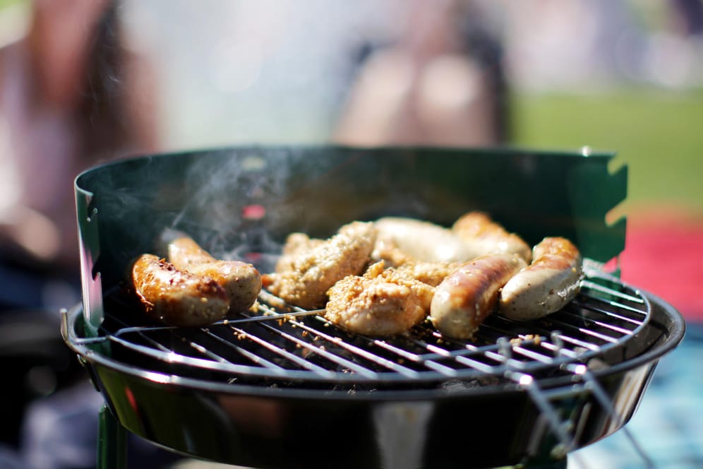 Würstchen liegen auf einem Grill: Wenn Fleischsaft in die Glut tropft, entstehen Giftstoffe.