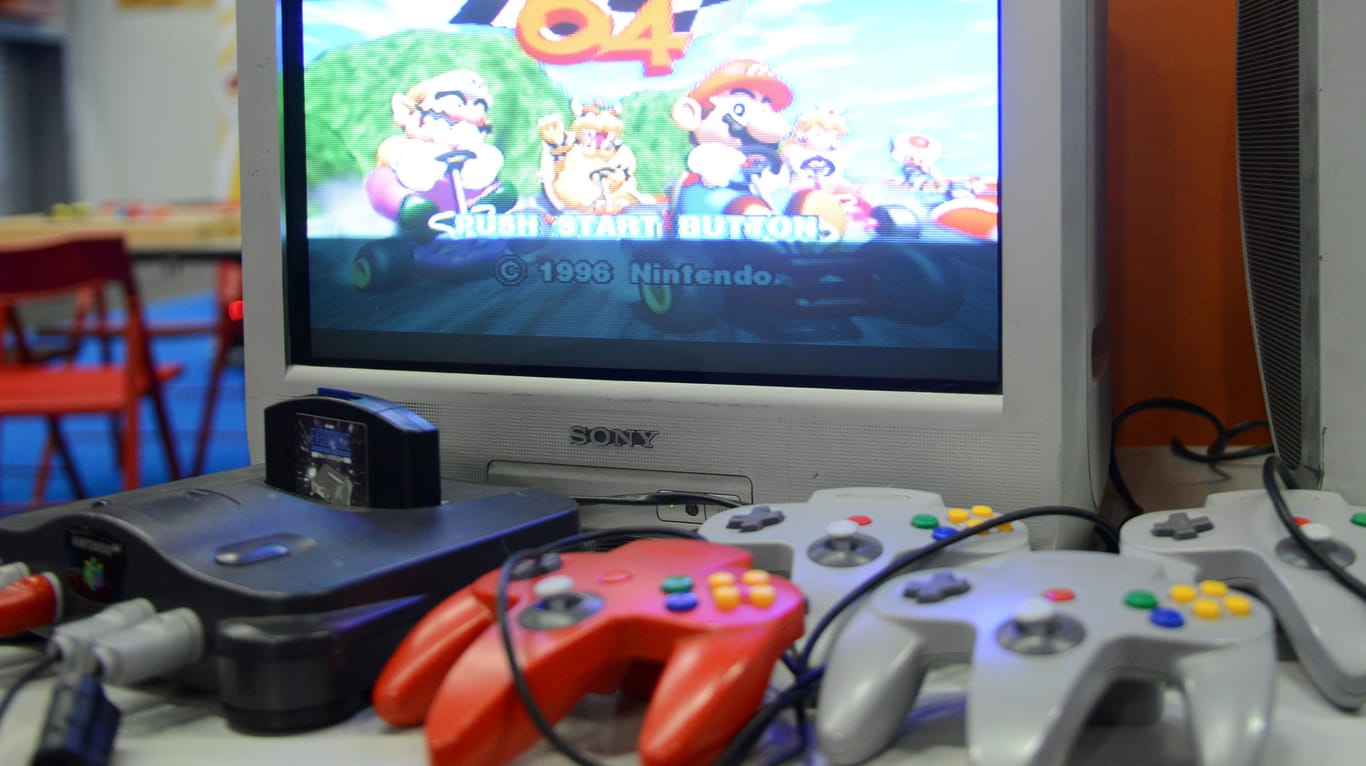 Klassiker: Eine Nintendo-64-Konsole mit Controllern. Auf dem Fernseher läuft das Rennspiel "Super Mario Kart 64".