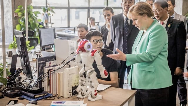 Zu Besuch beim Startup iCarbonX: Merkel im erkundigt sich bei einem Programmierer über den Stand der Forschung. Zu Besuch beim Startup iCarbonX: Merkel im erkundigt sich bei einem Programmierer über den Stand der Forschung.