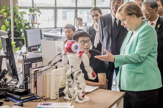Zu Besuch beim Startup iCarbonX: Merkel im erkundigt sich bei einem Programmierer über den Stand der Forschung.