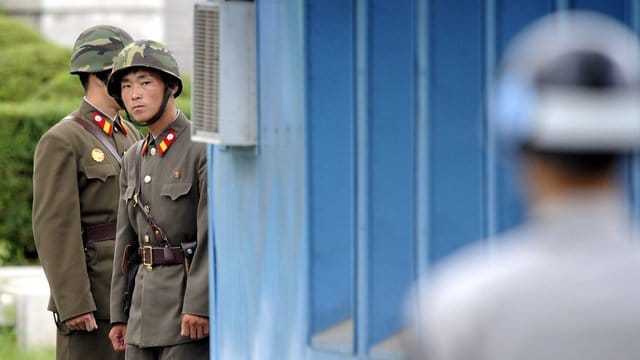Sichtkontakt: Nordkoreanische Soldaten (im Hintergrund) beobachten im Grenzort Panmunjom einen südkoreanischen Militärangehörigen. Sichtkontakt: Nordkoreanische Soldaten (im Hintergrund) beobachten im Grenzort Panmunjom einen südkoreanischen Militärangehörigen.