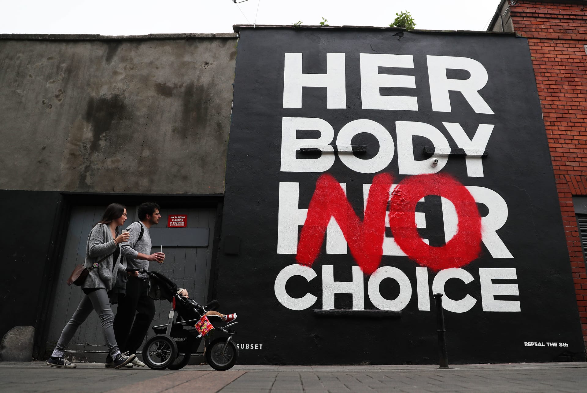 Eine Familie läuft an einem Poster der Künstlergruppe "Subse"t vorbei, das mit der Aufschrift "Ihr Körper Keine Wahl" zu einer Reform der Abtreibungsgesetze aufruft.