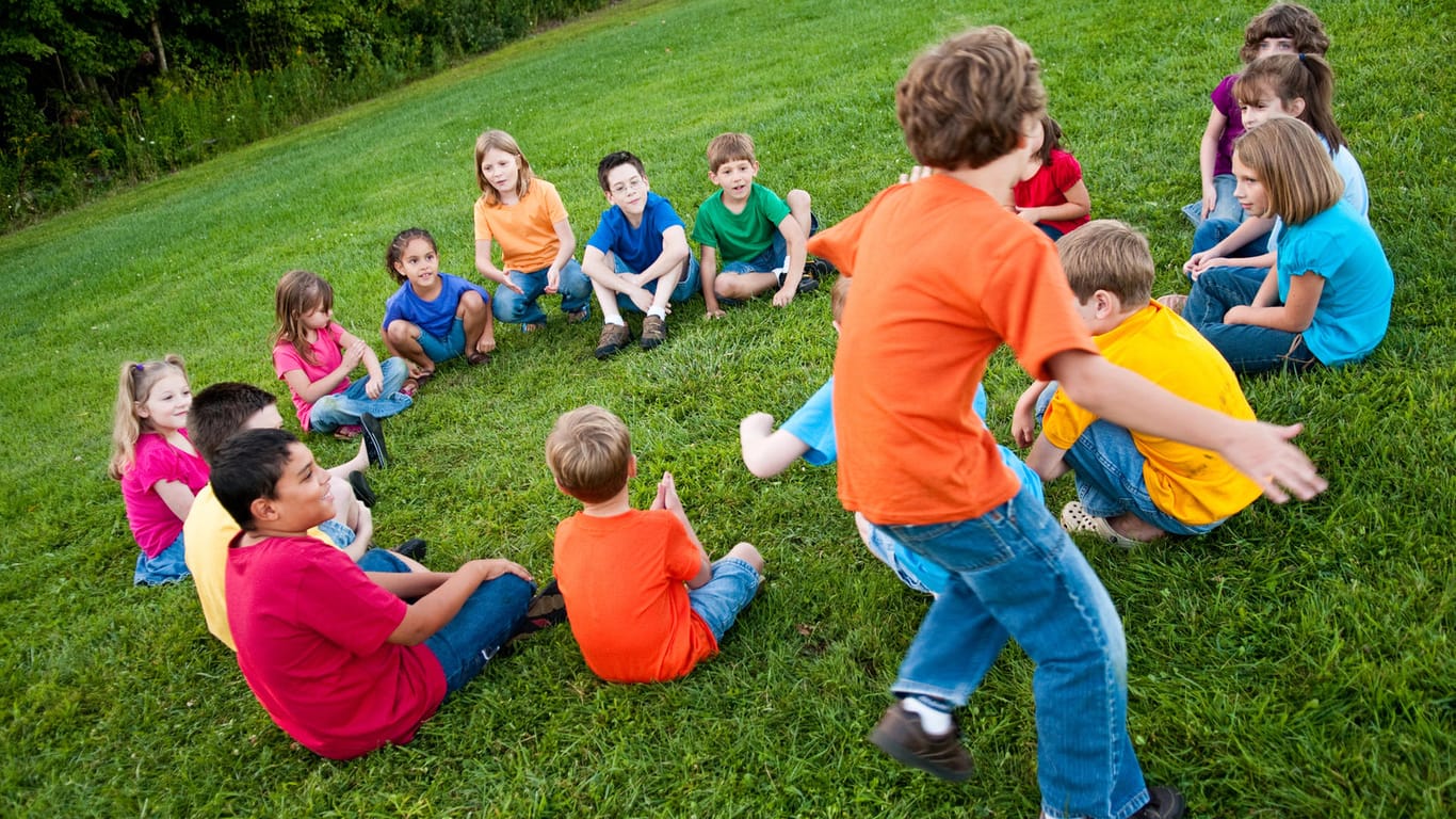 Kinder sitzen im Kreis: Bei dem Spiel "Faules Ei" müssen die Mitspieler aufmerksam und schnell sein.