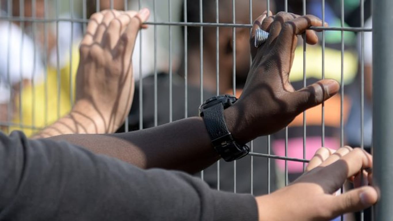 Hände an einem Zaun in einem Transitzentrum für Asylsuchende in Bayern.