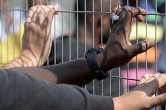 Hände an einem Zaun in einem Transitzentrum für Asylsuchende in Bayern.