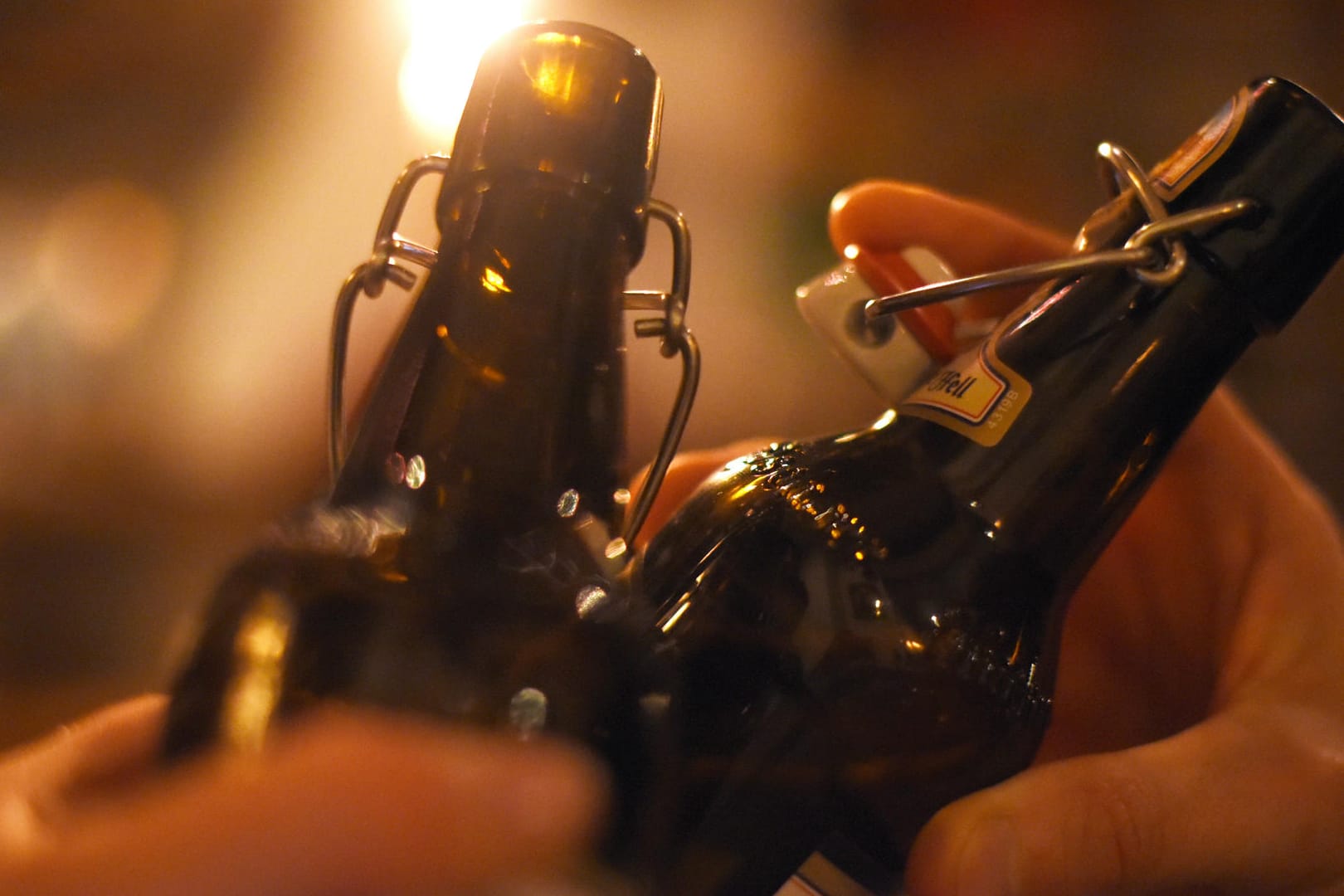 Zwei Menschen stoßen in einer Kneipe mit Flaschen-Bier an: Laut einer Studie haben Sperrzeiten kaum Einfluss auf Kriminalität in der Nacht.
