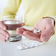 Frau hält drei Tabletten in der Handfläche