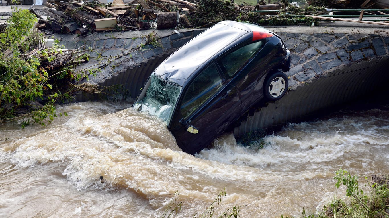 Rheinland-Pfalz, Herrstein: Ein vom Unwetter angeschwemmter PKW hängt an einer Brücke in Herrstein (Kreis Birkenfeld). Der Ort ist am Sonntag Abend von einem Unwetter teilweise überschwemmt worden.