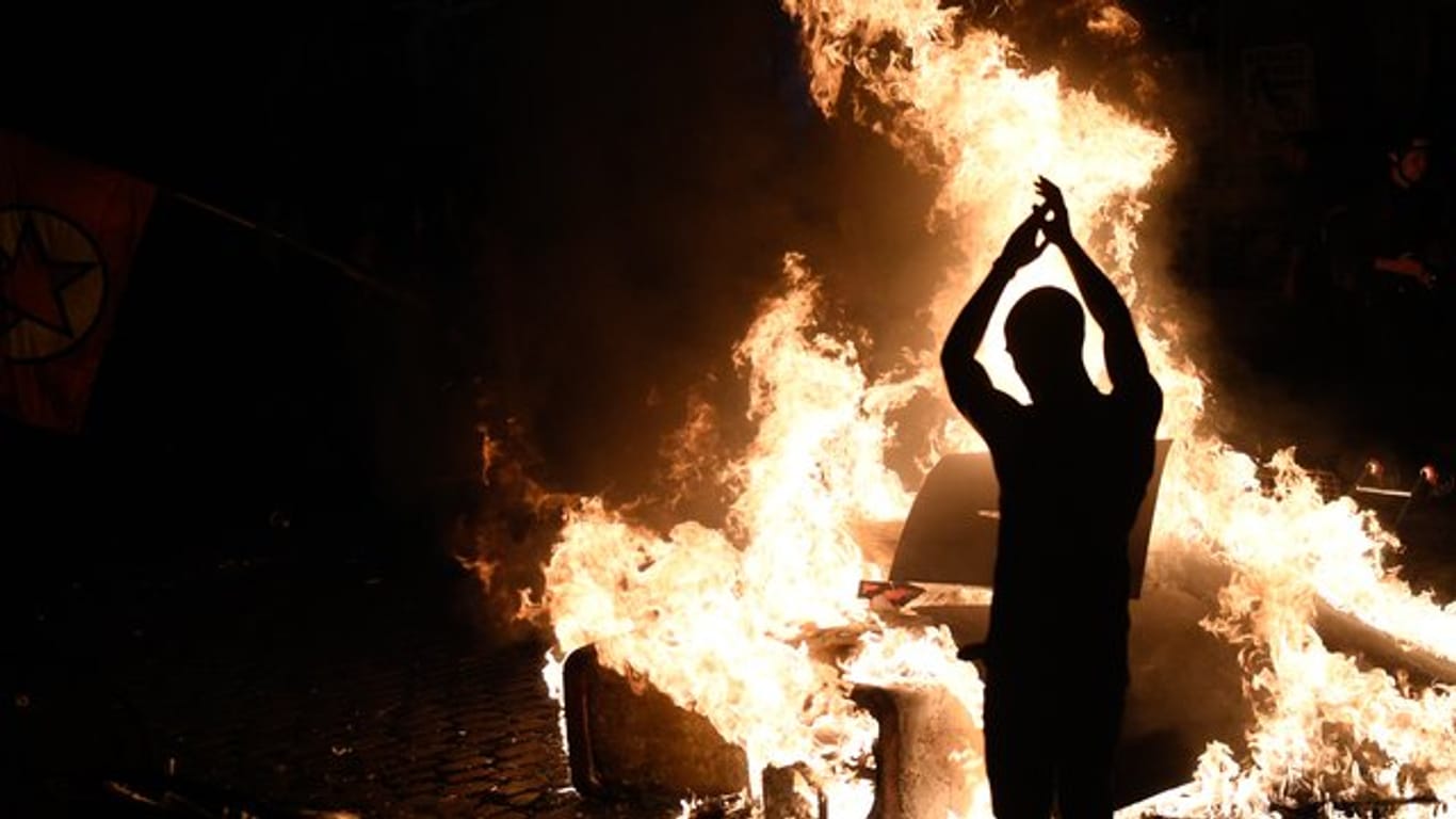 Ein Demonstrant wirft Holzstücke in eine brennende Barrikade.