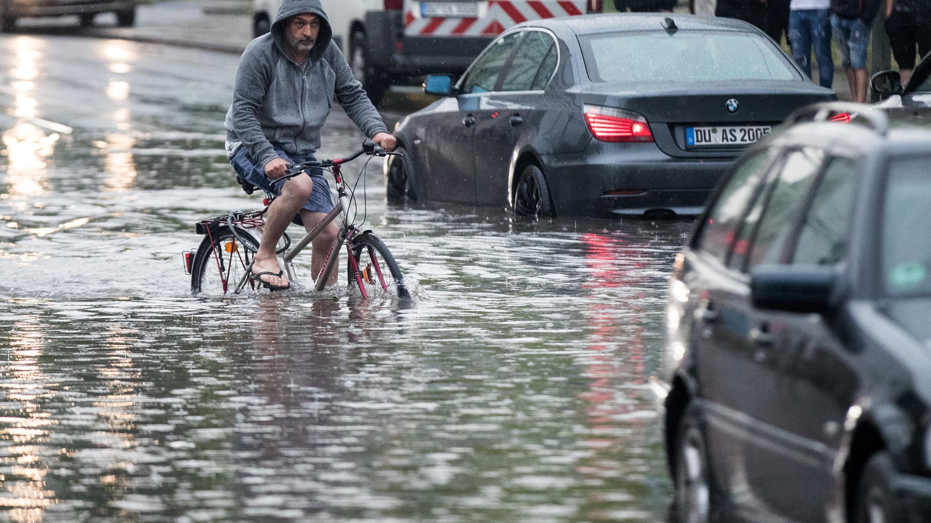 Unwetter in Duisburg: Ein Radfahrer fährt über eine überflutete Straße an liegengebliebenen Autos vorbei. Unwetter in Duisburg: Ein Radfahrer fährt über eine überflutete Straße an liegengebliebenen Autos vorbei.
