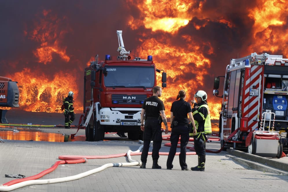 Einsatzkräfte der Polizei und Feuerwehr stehen bei dem Brand auf dem Gelände eines Entsorgungsunternehmens: Das Feuer konnte unter Kontrolle gebracht werden.