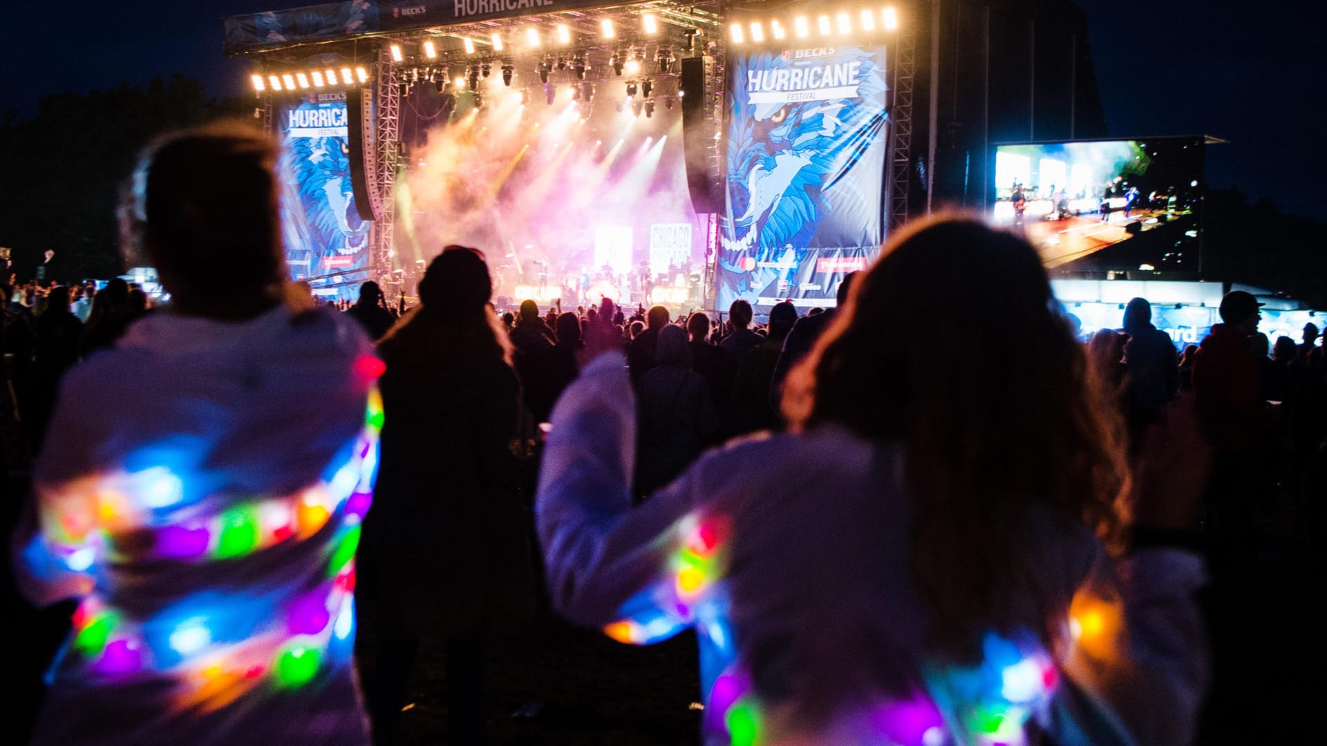 Hurricane Festival: Festivalbesucherinnen mit leuchtenden Jacken tanzen während des Musikfestivals.