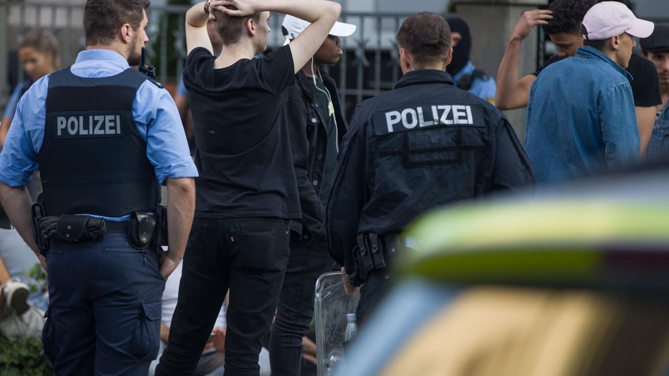 Polizisten bewachen am frühen Morgen eine Gruppe festgesetzter junger Männer: In der Nacht war es nach einem Musikfestival in Darmstadt zu Ausschreitungen gekommen.