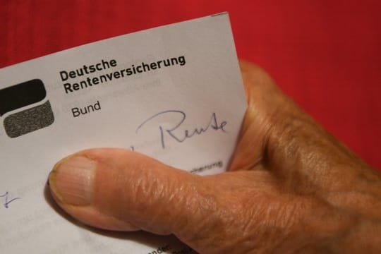 Eine Rentnerin hält ihren Rentenbescheid in der Hand.