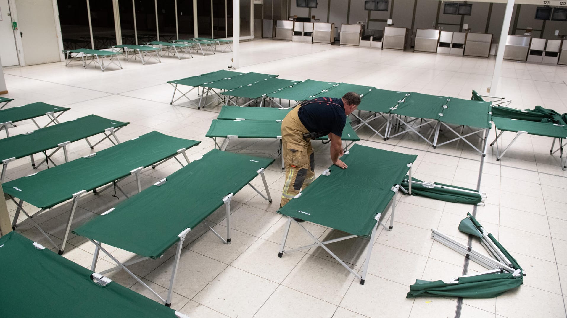 Ein Feuerwehrmann stellt Feldbetten im Hamburger Flughafen auf