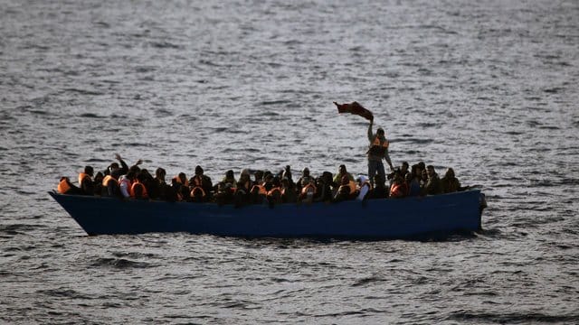 Ein Boot mit Flüchtlingen treibt auf dem Mittelmeer. Ein Boot mit Flüchtlingen treibt auf dem Mittelmeer.