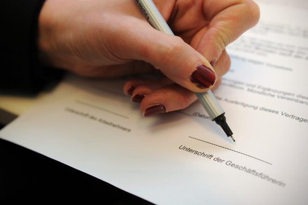 Eine Frau unterschreibt einen Arbeitsvertrag.