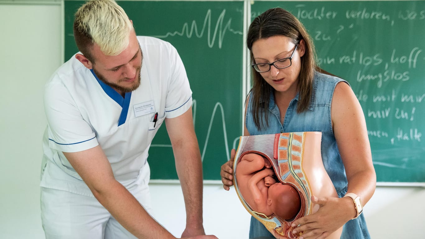 Jasmin Treiber-Meyer, Lehrhebamme am Klinikum Ansbach: Sie erklärt Konstantin Wroblewski an einem Modell aus Kunststoff anhand eines Querschnitts mit Baby im Bauch die Anatomie der Frau.