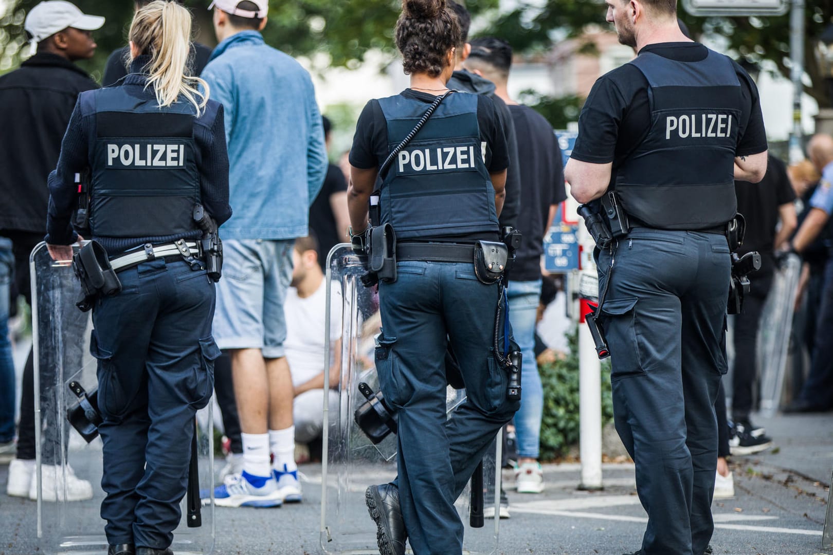 Polizisten bewachen am frühen Sonntagmorgen eine Gruppe festgesetzter junger Männer: Alle Verdächtigen sind nun wieder auf freiem Fuß – eine gemeinsame Motivation hatten sie laut Polizei nicht.