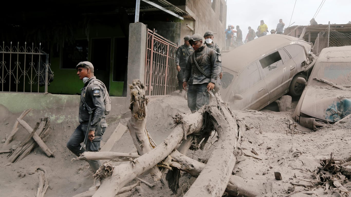 Policemen inspect at an area affected by the eruption of the Fuego volcano in the community of San Miguel Los Lotes in Escuintla