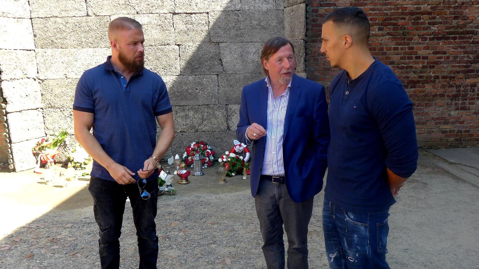 Nach der Niederlegung eines Blumengebindes an der Todeswand: Christoph Heubner, Vizepräsident des Internationalen Auschwitz Komitees, spricht mit den Rappern Kollegah und Farid Bang.