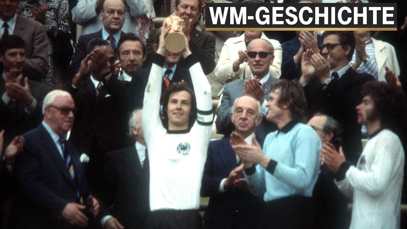 Franz Beckenbauer hält den Pokal hoch, daneben Paul Breitner und Sepp Maier.