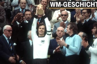 Franz Beckenbauer hält den Pokal hoch, daneben Paul Breitner und Sepp Maier.
