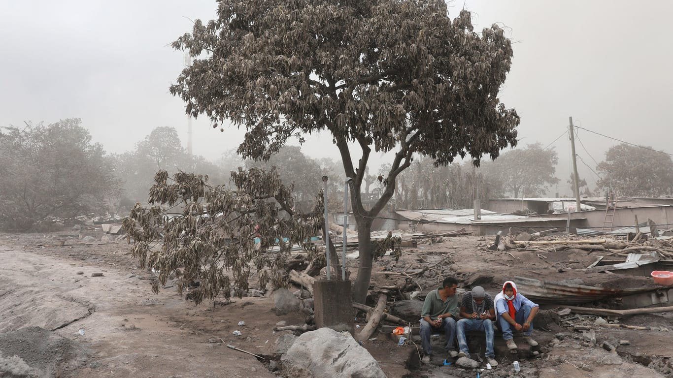 Anwohner machen eine Pause von der Aufräumarbeiten nach dem Vulkanausbruch in Guatemala: Zahl der Toten durch Vulkanausbruch in Guatemala steigt auf 109.