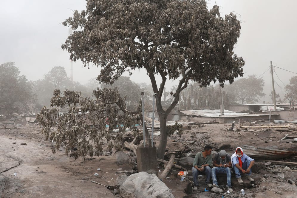 Anwohner machen eine Pause von der Aufräumarbeiten nach dem Vulkanausbruch in Guatemala: Zahl der Toten durch Vulkanausbruch in Guatemala steigt auf 109.