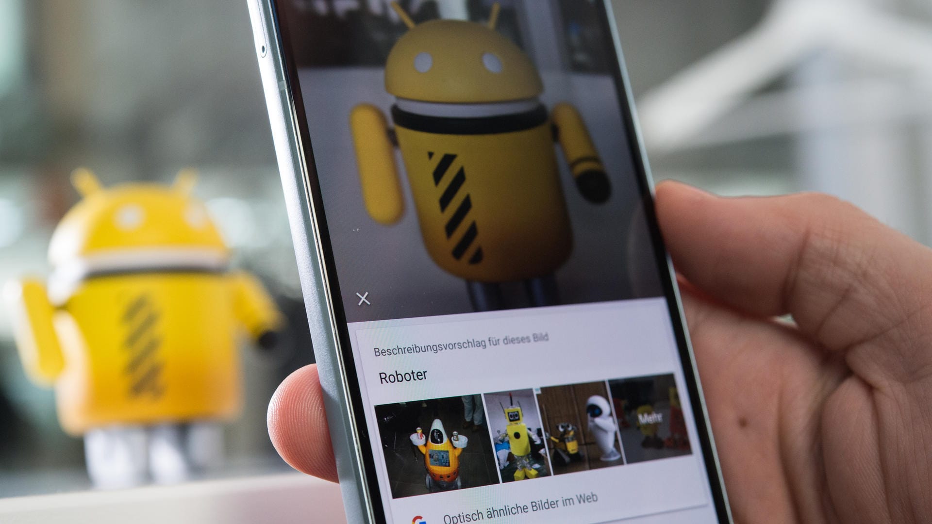 Ein Mann fotografiert mit dem Google Pixel 2 eine Android-Figur: Google Lens als alleinstehende App verfügbar.