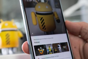 Ein Mann fotografiert mit dem Google Pixel 2 eine Android-Figur: Google Lens als alleinstehende App verfügbar.