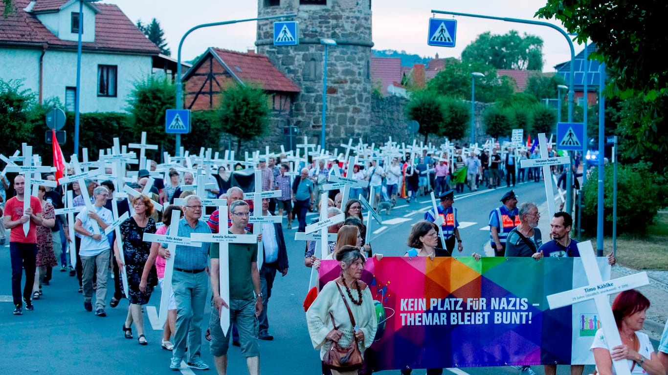 Der Zug der Gegendemonstration zieht mit weißen Kreuzen und einem Banner durch Themar.