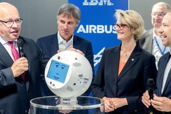 Peter Altmaier (l, CDU) sieht sich am Stand von IBM bei der Cebit den Weltraum-Roboter CIMON an.