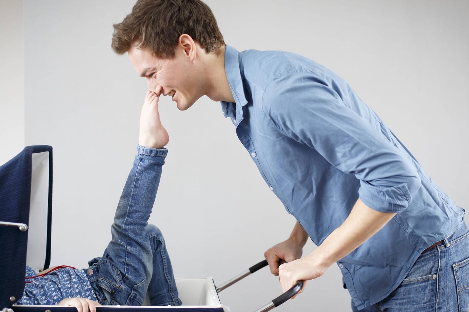 Ein junger Maenn steht vor einem Kinderwagen in dem ein Kind liegt Ein junger Maenn steht vor einem Kinderwagen in dem ein Kind liegt