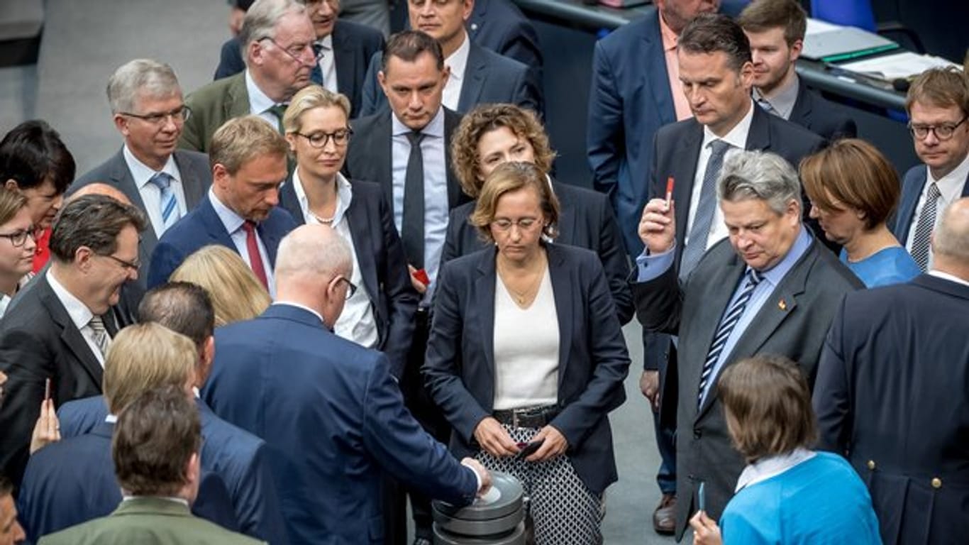 Bundestagsabgeordnete werfen im Plenum im Bundestag ihre Stimmkarten zur Abstimmung über die Parteienfinanzierung ein.