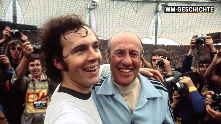 Überglücklich jubelnd liegen sich Franz Beckenbauer (links) und Trainer Helmut Schön nach dem 2:1-Sieg über die Niederlande im Endspiel der Fußball-Weltmeisterschaft am 07.07.1974 im Münchner Olympiastadion in den Armen.