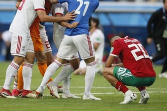 Der Marokkaner Aziz Bouhaddouz (r) hockt nach seinem Eigentor auf dem Rasen, während die Spieler des Iran den Sieg bejubeln.