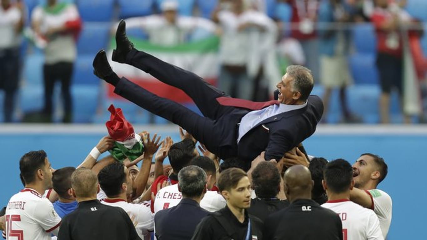 Irans Spieler lassen nach dem Sieg Trainer Carlos Queiroz hochleben.