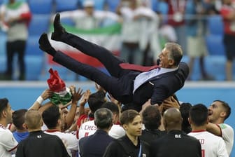 Irans Spieler lassen nach dem Sieg Trainer Carlos Queiroz hochleben.