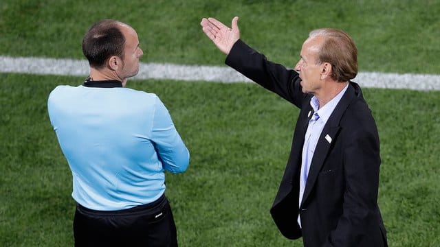 Nigerias Trainer Gernot Rohr (r) diskutiert beim Spiel gegen Kroatien mit dem vierten Schiedsrichter.