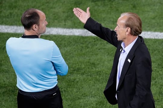 Nigerias Trainer Gernot Rohr (r) diskutiert beim Spiel gegen Kroatien mit dem vierten Schiedsrichter.