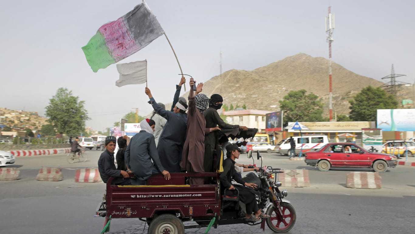 Kämpfe in Afghanistan: Talibankämpfer und ihre Anhänger tragen eine Darstellung der afghanischen Nationalflagge.