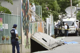 Ein Polizist hält vor einer Schule in Takatsuki in der Provinz Osaka Wache: Ein Mädchen wurde von der Wand eines Swimmingpools, die bei dem Erdbeben einstürzte, erschlagen.