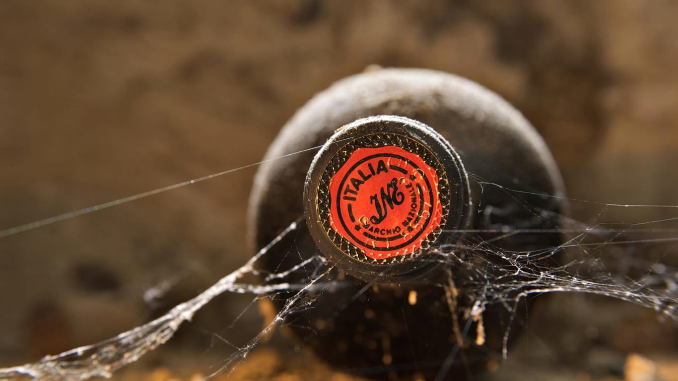 Eine Rotweinflasche mit Spinnenweben auf einem Symbolbild: Weine eines legendären Winzers sind für 30 Millionen Euro versteigert worden.