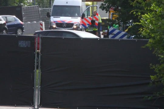 Rettungsfahrzeuge sind hinter Sichtschutz-Planen zu sehen.