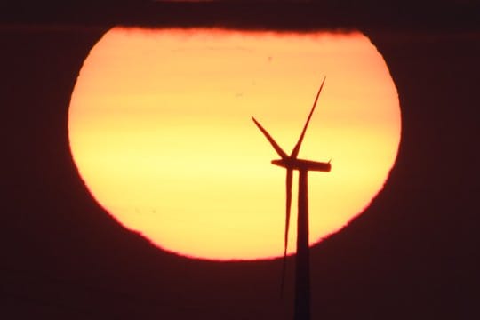 Sonnenaufgang hinter einem Windrad.